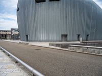 a skateboarder riding near a skate ramp in front of a large building with two round openings