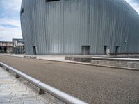 a skateboarder riding near a skate ramp in front of a large building with two round openings