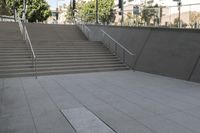 a boy is skateboarding down a concrete sidewalk by stairs and trees outside an office building