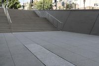 a boy is skateboarding down a concrete sidewalk by stairs and trees outside an office building