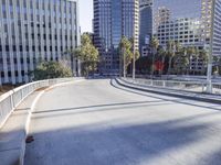 a skateboarder is riding along the empty city street in front of the skyscrapers