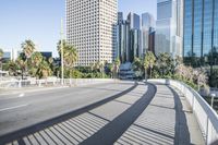 a skateboarder is riding along the empty city street in front of the skyscrapers