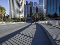 a skateboarder is riding along the empty city street in front of the skyscrapers