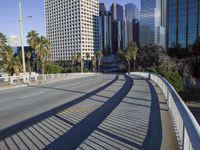 a skateboarder is riding along the empty city street in front of the skyscrapers