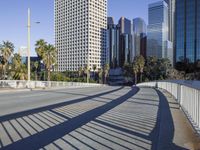 a skateboarder is riding along the empty city street in front of the skyscrapers