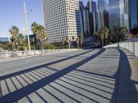 a skateboarder is riding along the empty city street in front of the skyscrapers