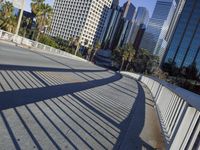 a skateboarder is riding along the empty city street in front of the skyscrapers
