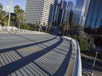a skateboarder is riding along the empty city street in front of the skyscrapers