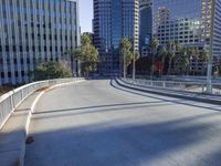 a skateboarder is riding along the empty city street in front of the skyscrapers