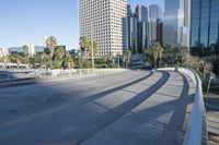 a skateboarder is riding along the empty city street in front of the skyscrapers
