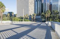 a skateboarder is riding along the empty city street in front of the skyscrapers