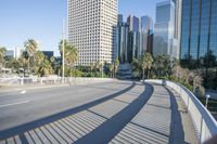 a skateboarder is riding along the empty city street in front of the skyscrapers