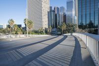 a skateboarder is riding along the empty city street in front of the skyscrapers