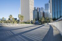 a skateboarder is riding along the empty city street in front of the skyscrapers