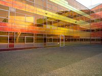 a man skateboarding on pavement in front of a glass building while the sun is going down