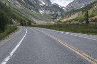 there is a skate boarder riding along the side of the road at the mountains