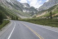 there is a skate boarder riding along the side of the road at the mountains