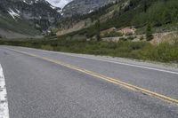 there is a skate boarder riding along the side of the road at the mountains