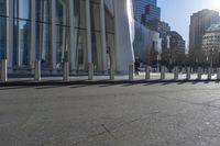 a skateboarder riding down the side of an empty city street, surrounded by glass and concrete buildings