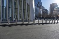 a skateboarder riding down the side of an empty city street, surrounded by glass and concrete buildings