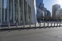 a skateboarder riding down the side of an empty city street, surrounded by glass and concrete buildings