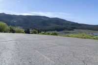 a man riding a skateboard on top of a paved surface near mountains and trees