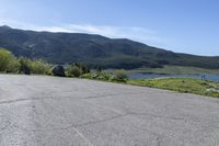 a man riding a skateboard on top of a paved surface near mountains and trees