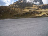 a person on a skateboard is in the road near a mountain slope and bridge