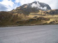 a person on a skateboard is in the road near a mountain slope and bridge
