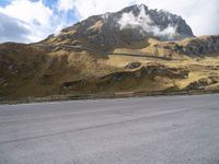 a person on a skateboard is in the road near a mountain slope and bridge