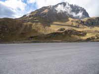 a person on a skateboard is in the road near a mountain slope and bridge