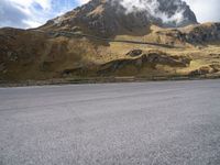 a person on a skateboard is in the road near a mountain slope and bridge