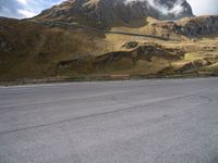 a person on a skateboard is in the road near a mountain slope and bridge