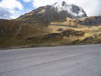 a person on a skateboard is in the road near a mountain slope and bridge