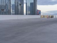 a young person riding a skate board on a ramp of a parking lot, surrounded by tall buildings