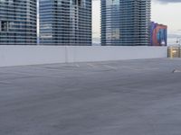 a young person riding a skate board on a ramp of a parking lot, surrounded by tall buildings