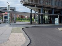 a man skateboarding on pavement near building with glass windows and walkway around it,