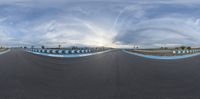 a man riding a skateboard down a half pipe on a race track with clouds behind him