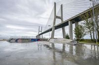 a skateboarder is sitting in front of a bridge in the rain with his skateboard in hand