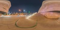 skateboarding ramp in front of a large modern building at night with skyscrapers in the background