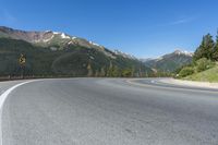 a person riding a skateboard on a road by a mountainous setting with mountains in the background