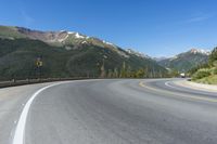 a person riding a skateboard on a road by a mountainous setting with mountains in the background