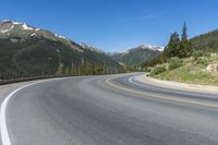 a person riding a skateboard on a road by a mountainous setting with mountains in the background