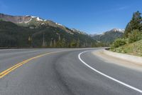 a person riding a skateboard on a road by a mountainous setting with mountains in the background