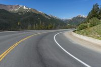 a person riding a skateboard on a road by a mountainous setting with mountains in the background