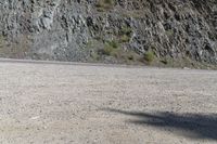 a person riding a skateboard on the road between two large mountains on one side and a sky background