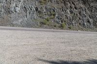 a person riding a skateboard on the road between two large mountains on one side and a sky background