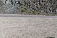 a person riding a skateboard on the road between two large mountains on one side and a sky background