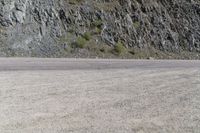 a person riding a skateboard on the road between two large mountains on one side and a sky background