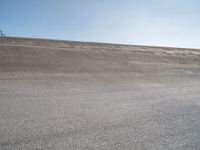 a lone skateboard on the road in a dry field with sky in the background